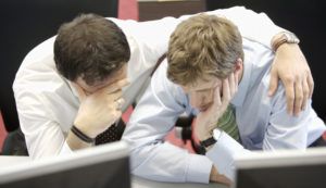 Businessman with arm around male coworker at desk