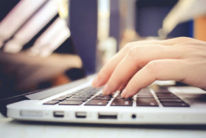 Female hands typing on keyboard of laptop